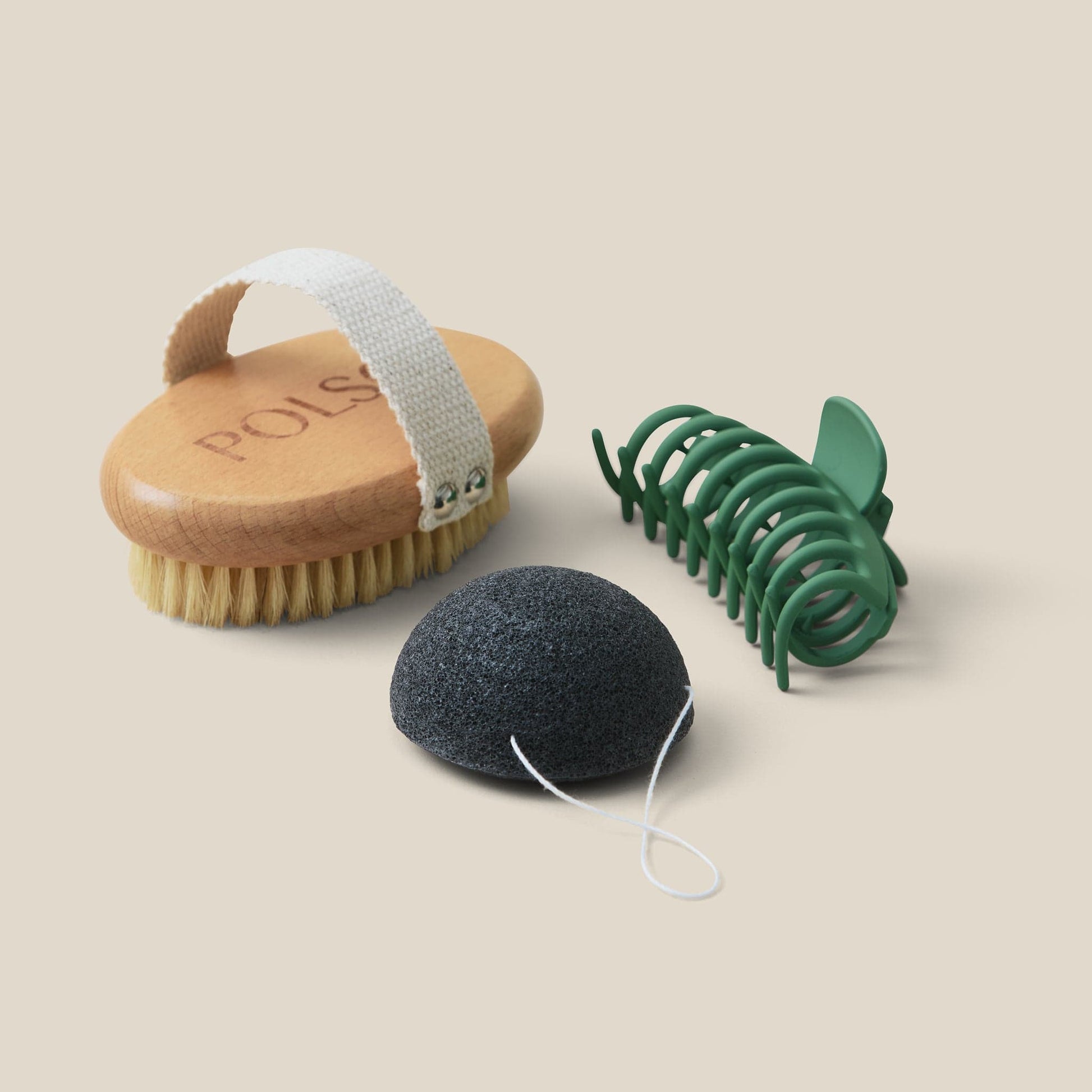 flat lay image of dry brush, green hair clip and Konjac cleansing sponge
