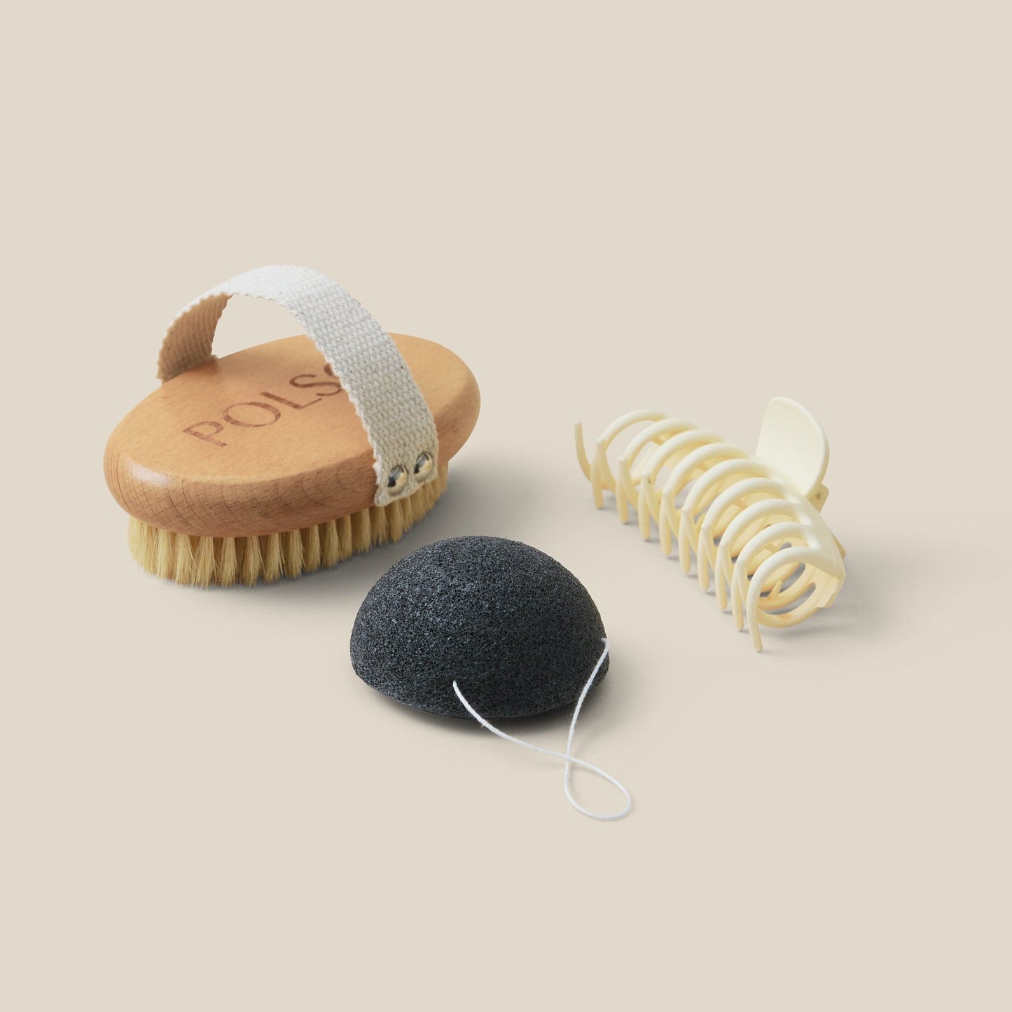 flat lay image of dry brush, white hair clip and Konjac cleansing sponge