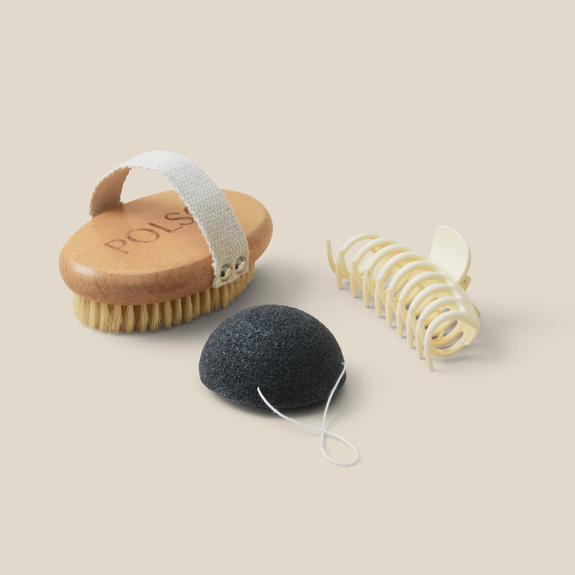 flat lay image of dry brush, white hair clip and Konjac cleansing sponge
